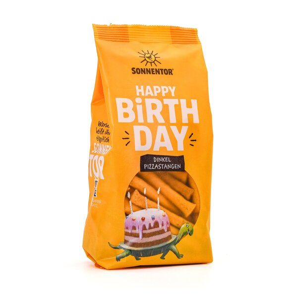SONNENTOR Happy Birthday Spelt Pizza Sticks. Yellow packaging with an illustration of a turtle carrying a cake with candles on its back. The elongated snack can be seen through the window.