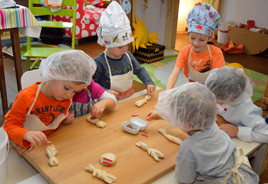 Auf dem Foto sind mehrere Kinder mit Haarnetzten beim Backen zu sehen. | © SONNENTOR