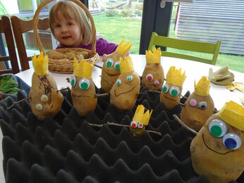 Auf dem Foto ist ein Mädchen zu sehen. Davor sind dekorierte Kartoffeln zu sehen. | © SONNENTOR